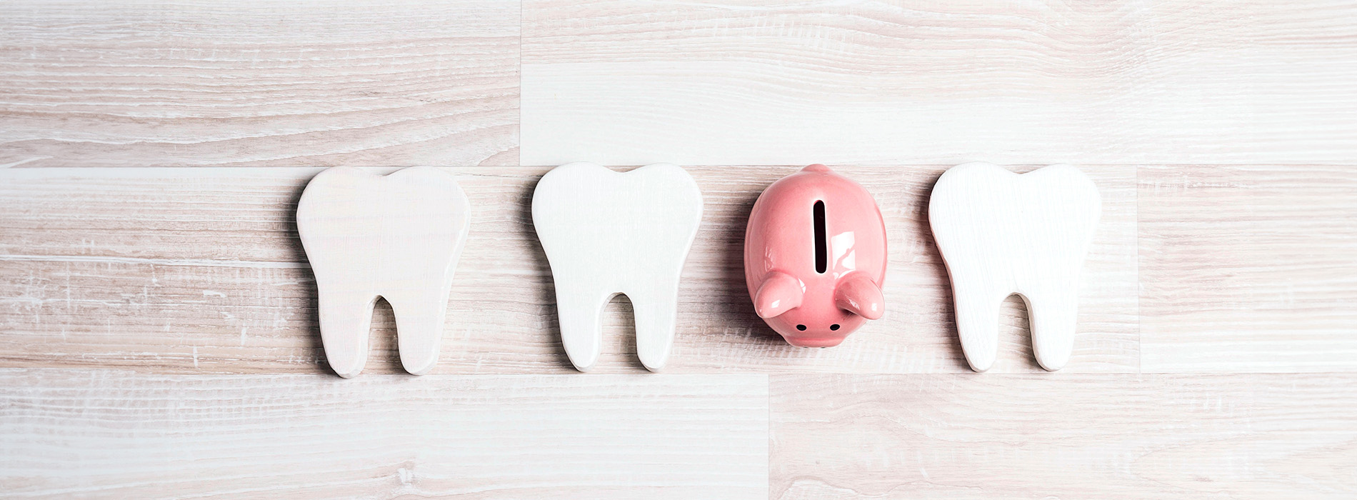 An image of a white cutting board with three wooden toothpicks and four pink piggy banks, arranged in a vertical row against a blurred background.