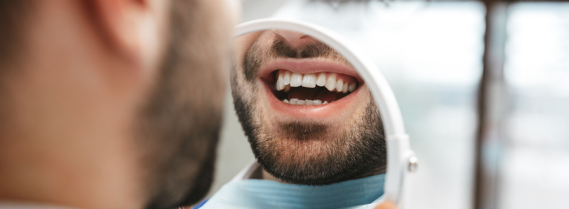 A man with a toothbrush in his mouth, captured in mid-brush against a blurred background.